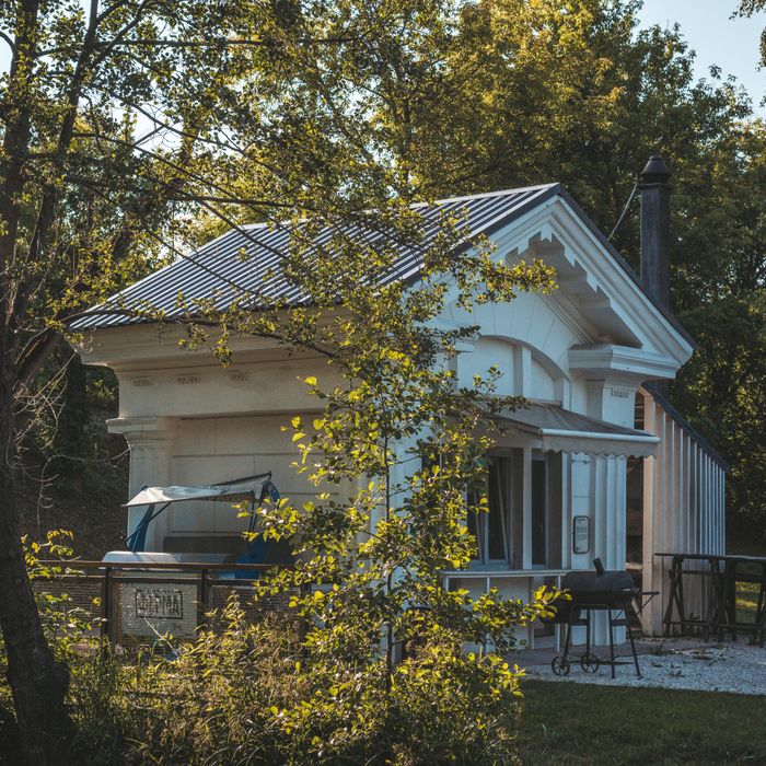 Serene white cabin nestled in autumn foliage, showcasing country living charm.