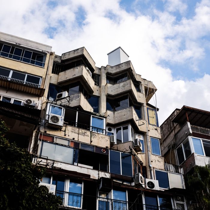 Low-angle view of a weathered apartment building under a partially cloudy sky.