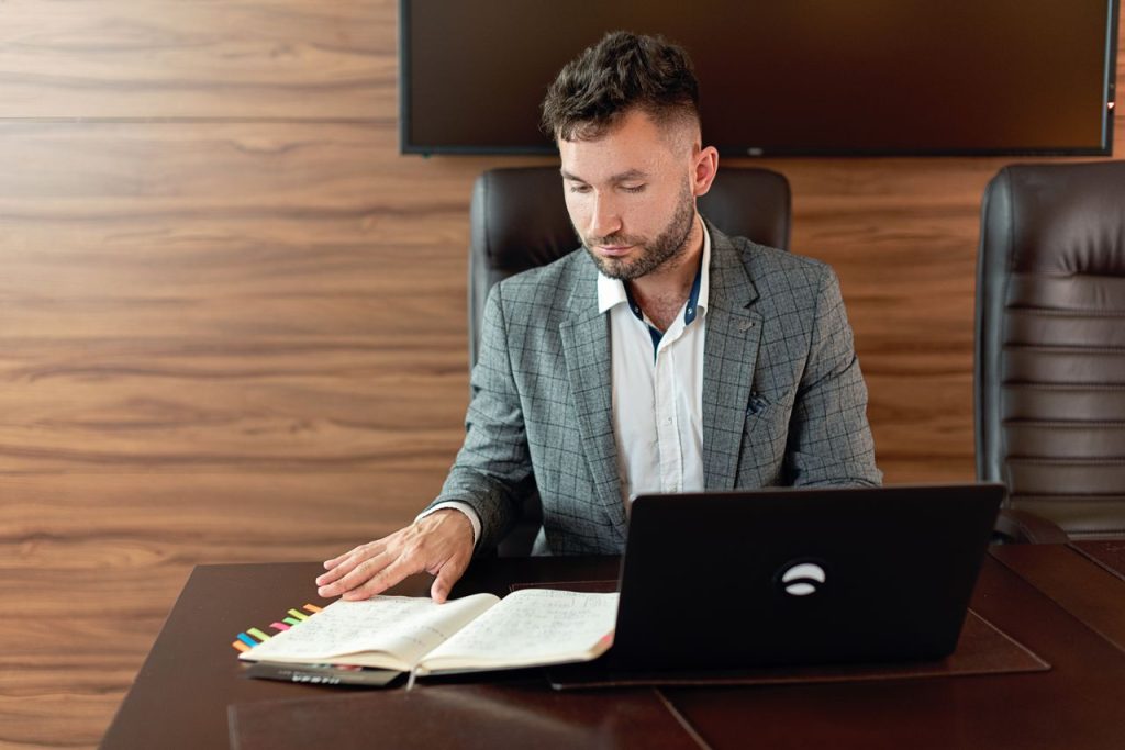 Focused man working on laptop and notes in a modern office.